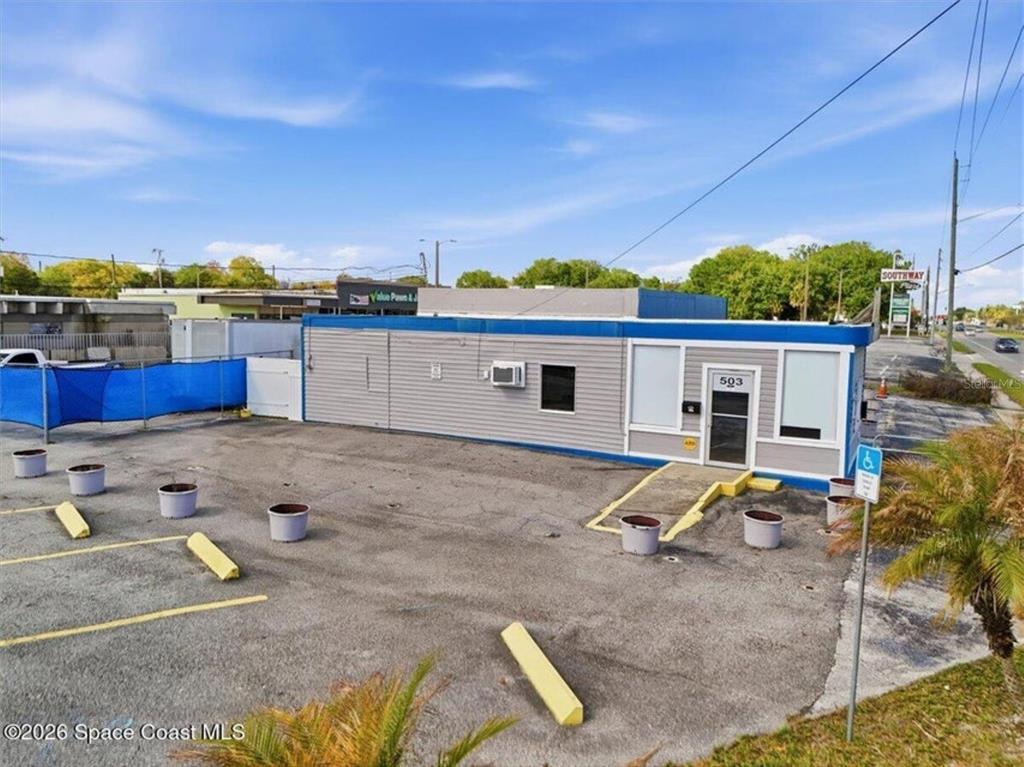 A single-story commercial building with gray siding and a paved parking lot in front — 503 CHENEY HIGHWAY, TITUSVILLE, FL