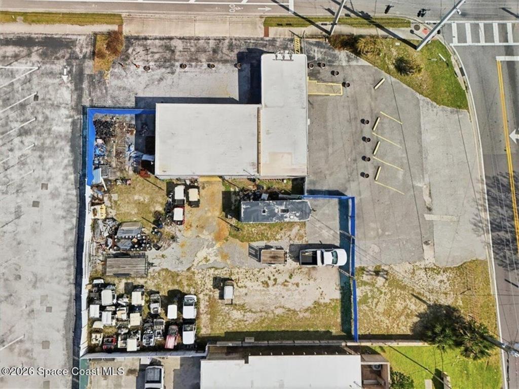 An aerial view shows a commercial building with a fenced outdoor storage yard and parking — 503 CHENEY HIGHWAY, TITUSVILLE, FL