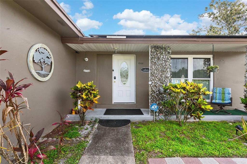 The exterior of a house features a white front door, a concrete walkway, and landscaping — 1566 PROVIDENCE BOULEVARD, DELTONA, FL