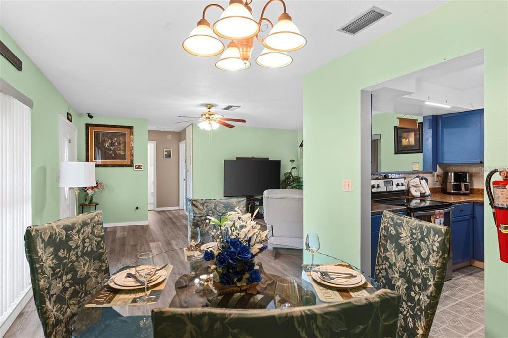 A dining area with a glass table and floral chairs opens into a living room — 1566 PROVIDENCE BOULEVARD, DELTONA, FL