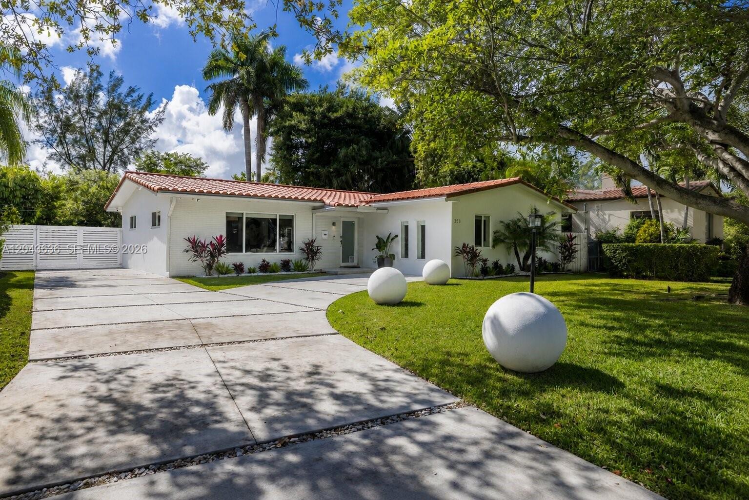 A white single-story house with a red tile roof features a concrete driveway and lawn — 200 NW 86th St, El Portal FL 33138, EL PORTAL, FL