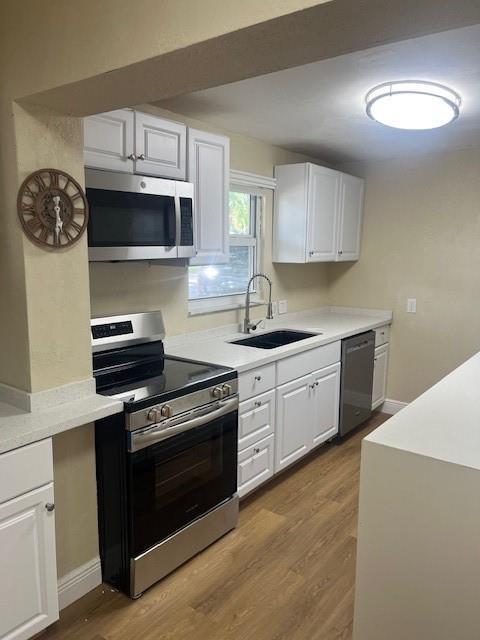 A kitchen features white cabinets, stainless steel appliances, a dark sink, and light wood flooring — 734 SW 8th Street, Dania Beach FL 33004, DANIA BEACH, FL