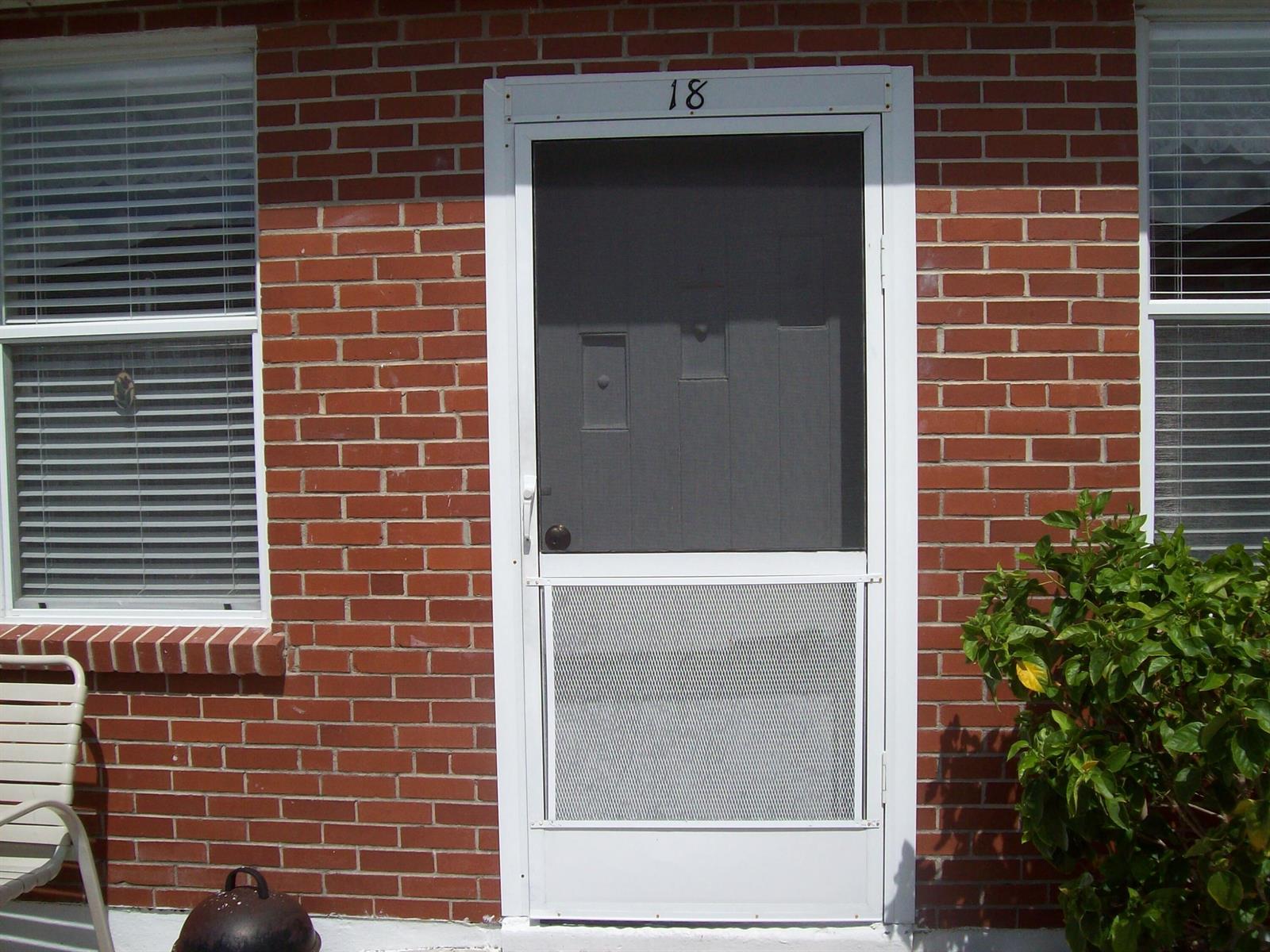 A white screen door with the number 18 above it on a red brick exterior — 908 Villas Drive # 18, Venice FL 34285, VENICE, FL