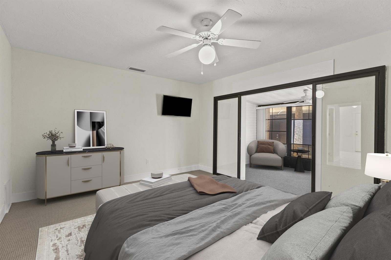 This bedroom features a ceiling fan, a dresser, and a glass-enclosed sunroom with seating — 908 Villas Drive # 18, Venice FL 34285, VENICE, FL