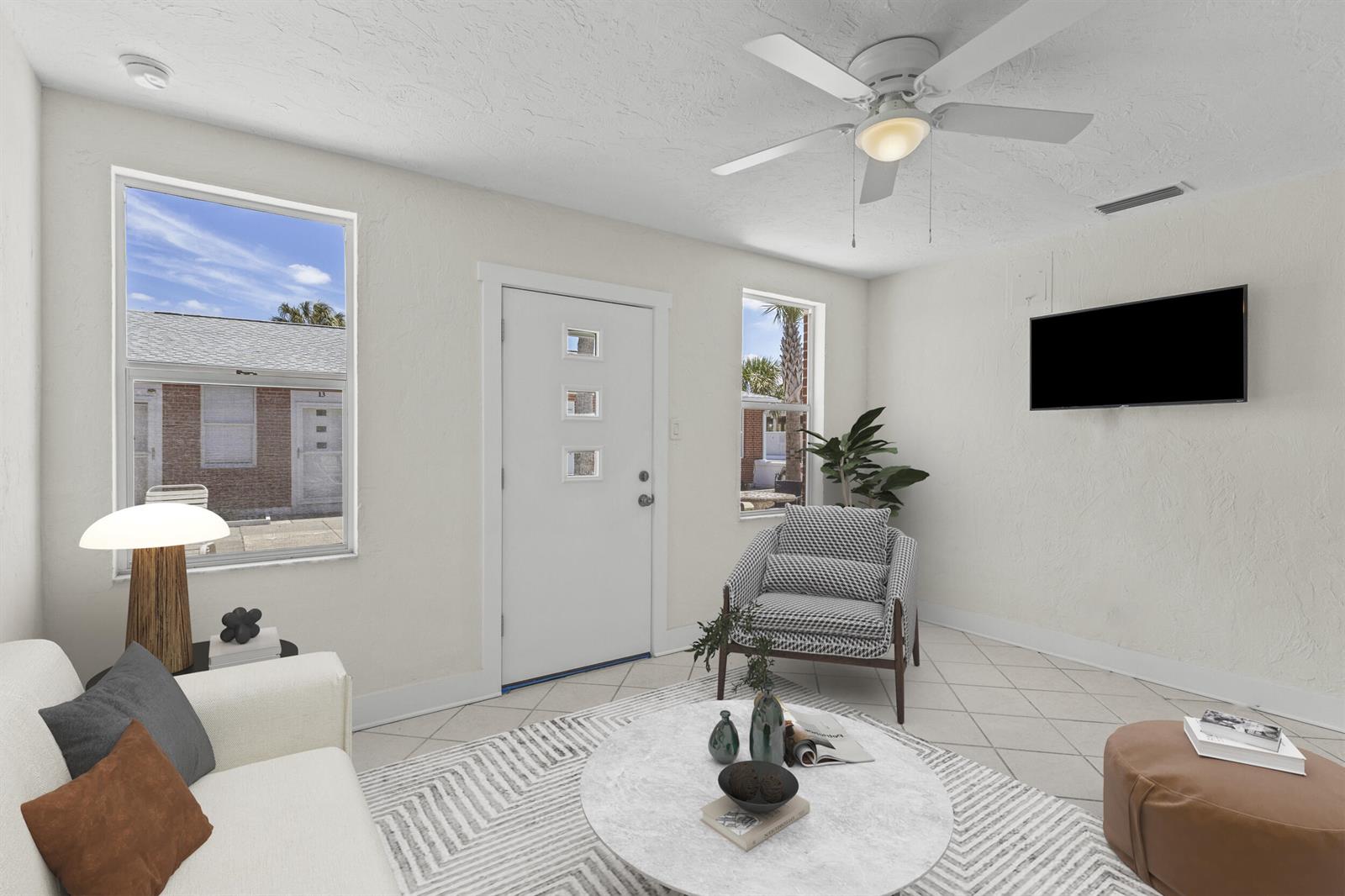 A bright living room features white walls, tile flooring, a ceiling fan, and a front door — 908 Villas Drive # 18, Venice FL 34285, VENICE, FL