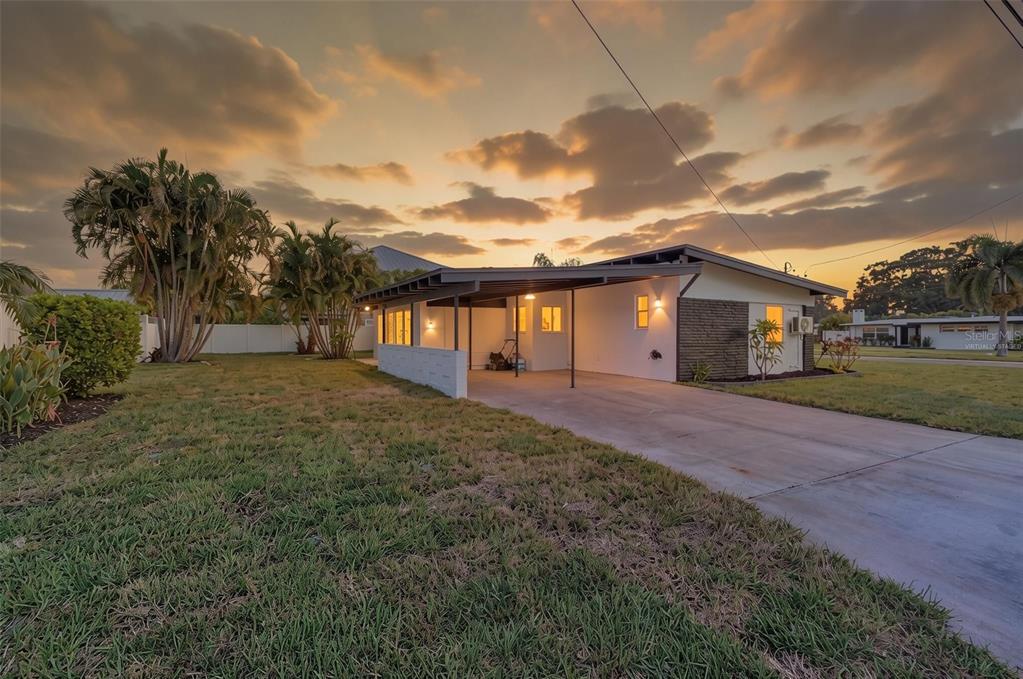 A single-story house with a carport and a large lawn under a sunset sky — 63 PALM BOULEVARD, DUNEDIN, FL
