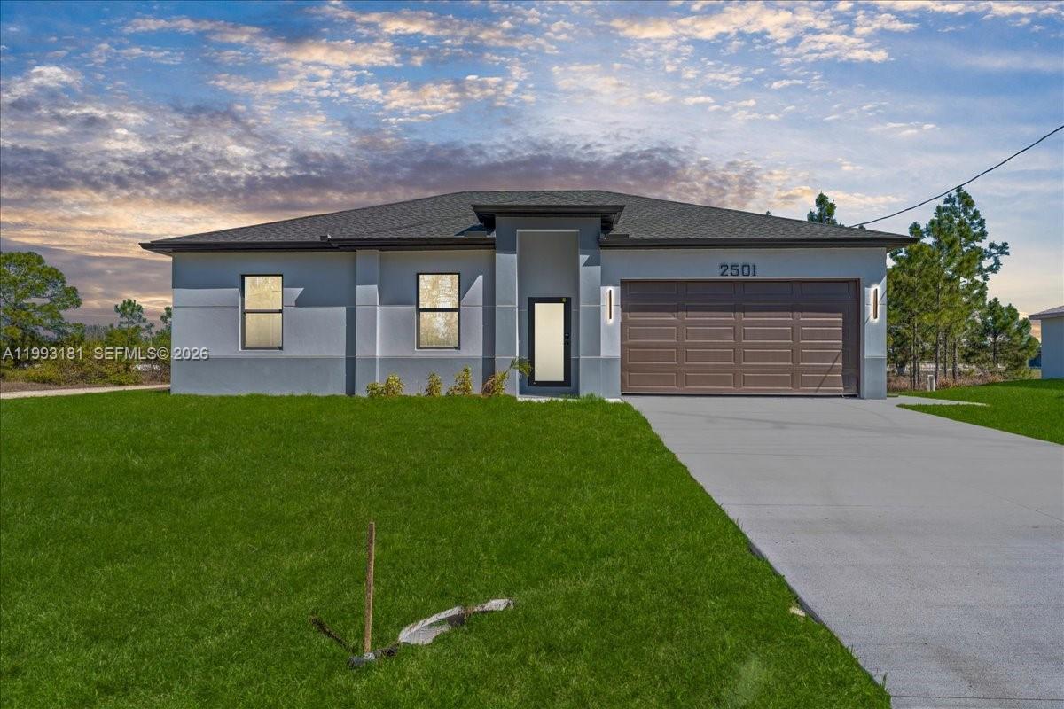 A single-story gray house with a two-car garage and a concrete driveway — 2501 E 15TH ST, Lehigh Acres FL 33972, LEHIGH ACRES, FL