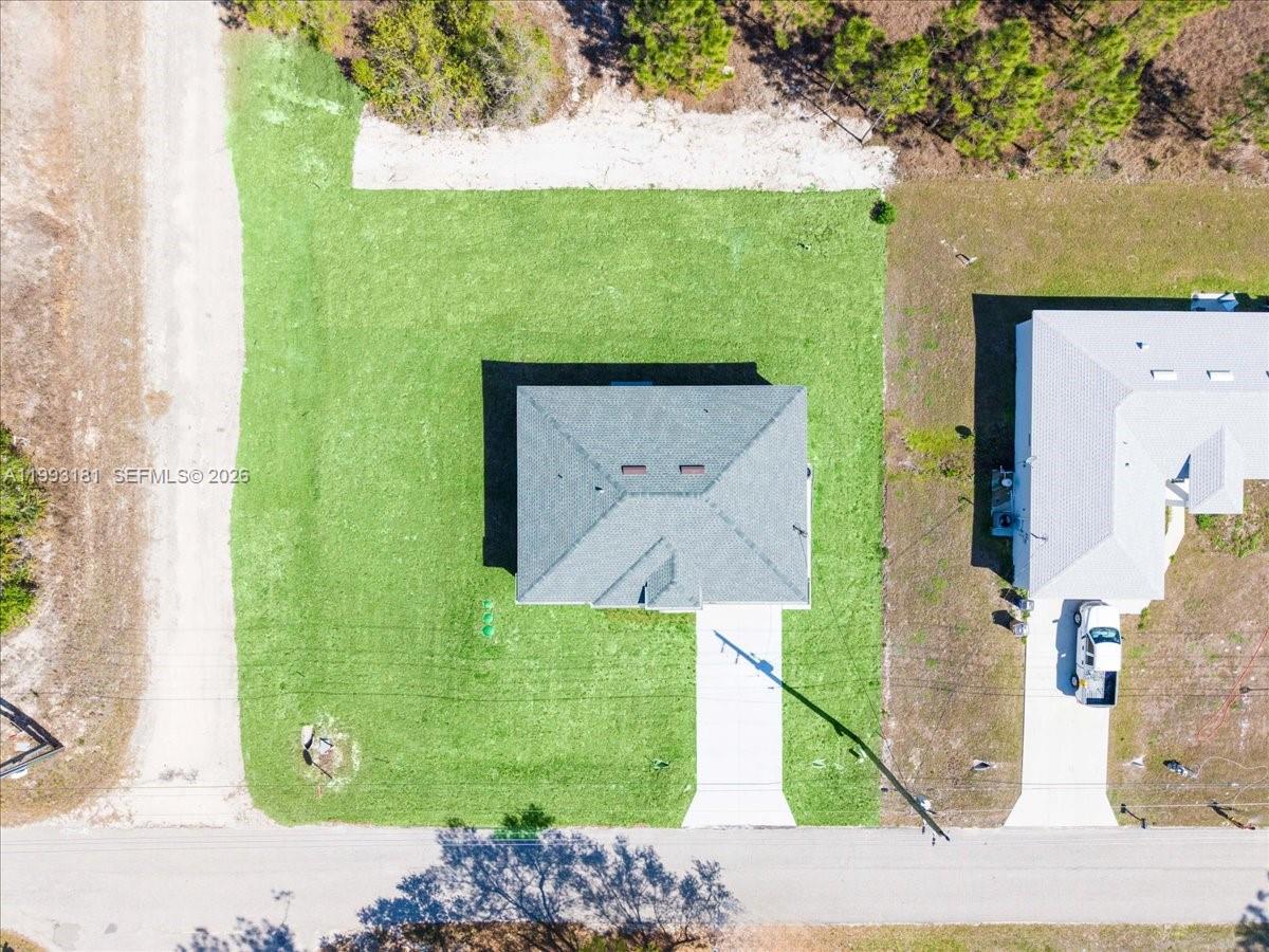 An aerial view shows a house with a gray roof centered on a grassy lot — 2501 E 15TH ST, Lehigh Acres FL 33972, LEHIGH ACRES, FL