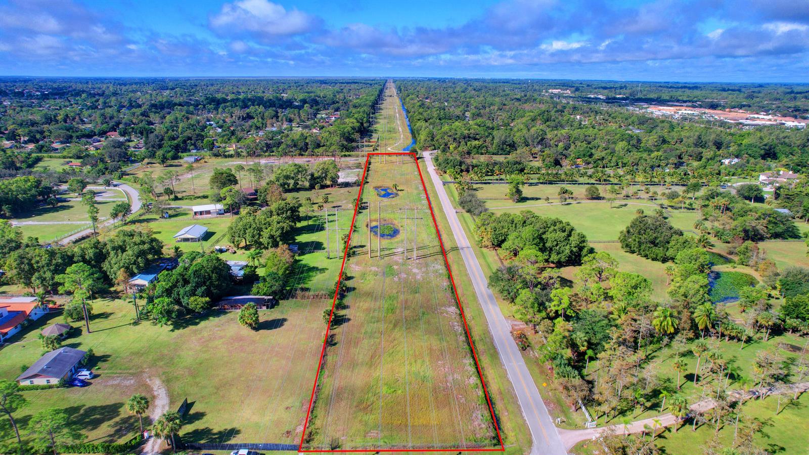 An aerial view shows a long, rectangular plot of land bordered by a road and trees — 0000 Acme Road, Wellington FL 33414, WELLINGTON, FL