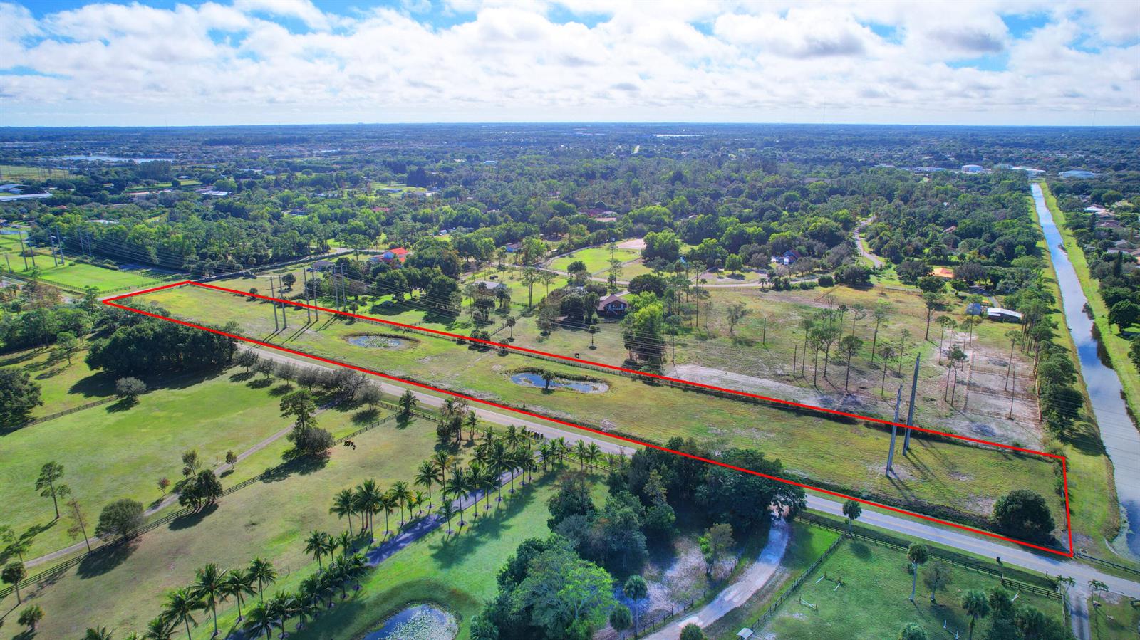 An aerial view shows a long, rectangular plot of land outlined in red near a canal — 0000 Acme Road, Wellington FL 33414, WELLINGTON, FL