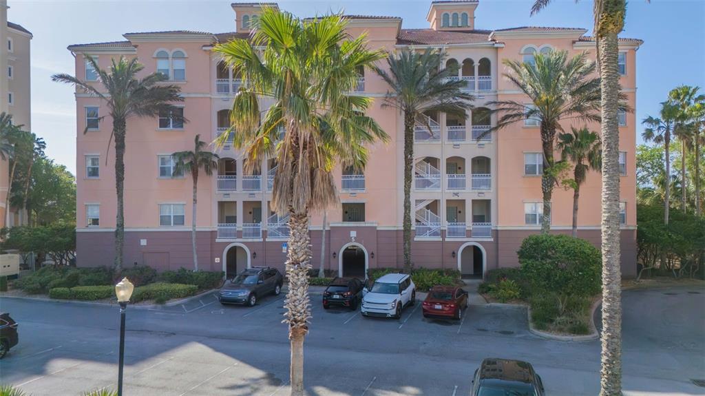 A multi-story peach-colored apartment building features palm trees and a parking lot in front — 5 OCEAN CREST WAY UNIT 1411, PALM COAST, FL