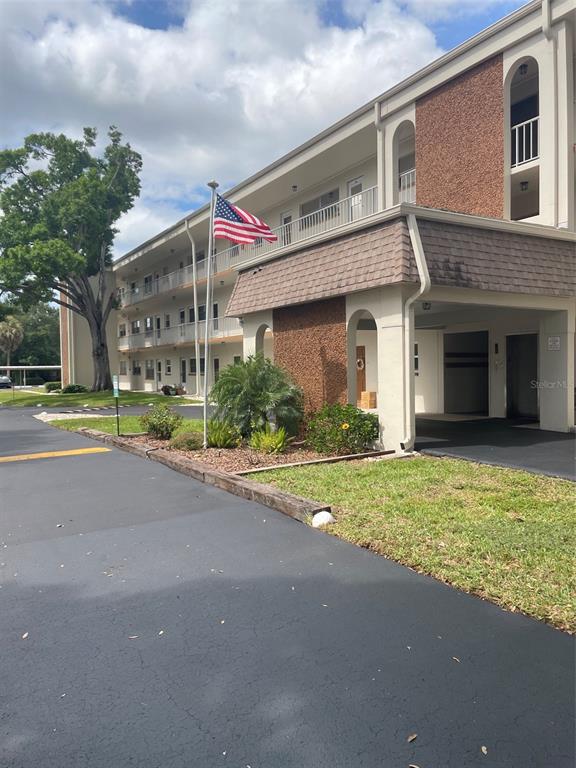 A multi-story apartment building features a covered entrance, a brick facade, and an American flag — 5880 38TH AVENUE N UNIT 206, ST PETERSBURG, FL