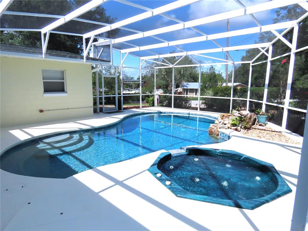 A screened-in pool area features a kidney-shaped swimming pool and a raised octagonal hot tub — 787 N WATERVIEW DRIVE, CLERMONT, FL