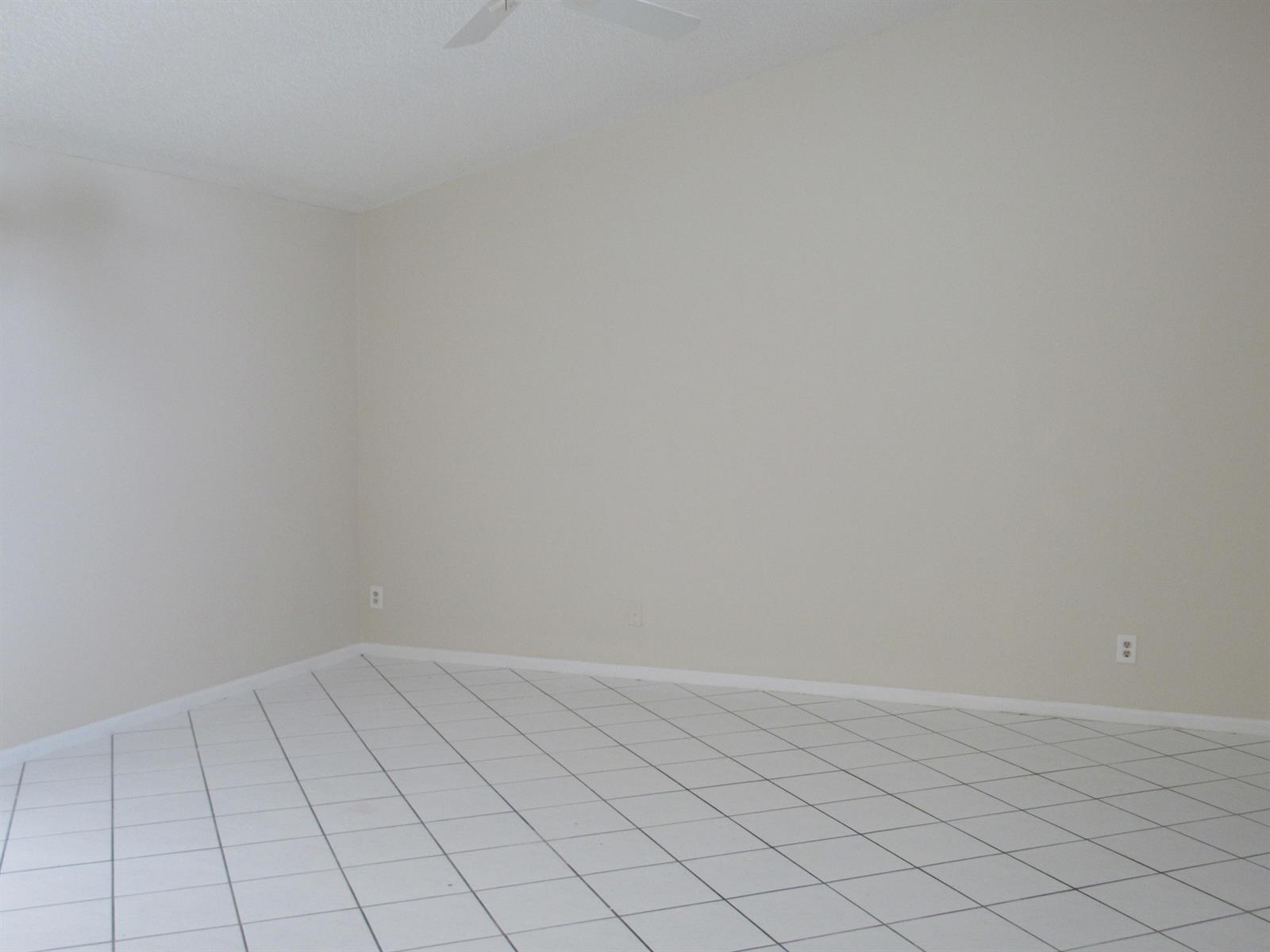 An empty room with white walls, white tile flooring, and a ceiling fan — 1065 Manor Drive, Palm Springs FL 33461, PALM SPRINGS, FL