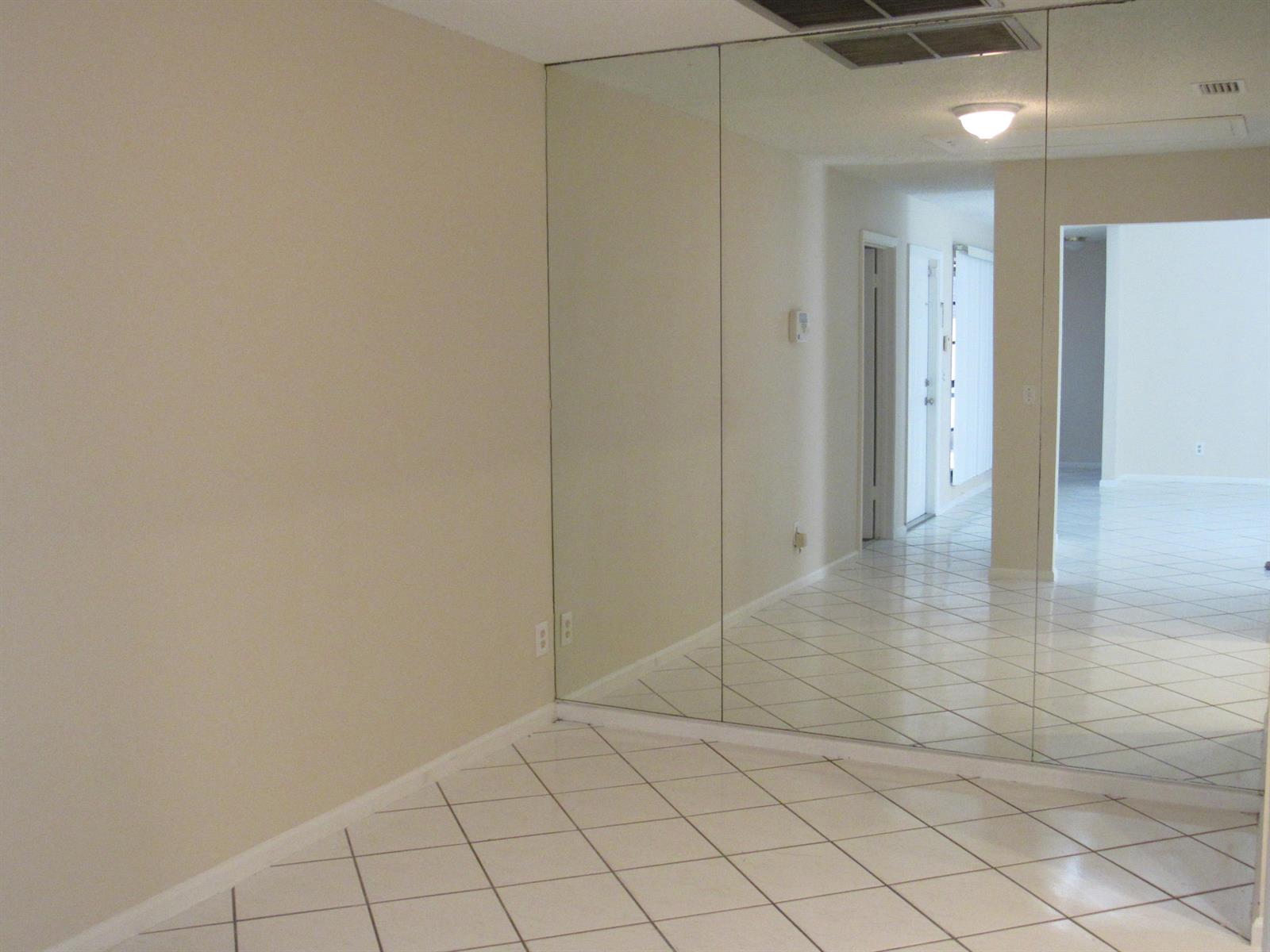 A room with white tile flooring and a large wall-to-wall mirror — 1065 Manor Drive, Palm Springs FL 33461, PALM SPRINGS, FL