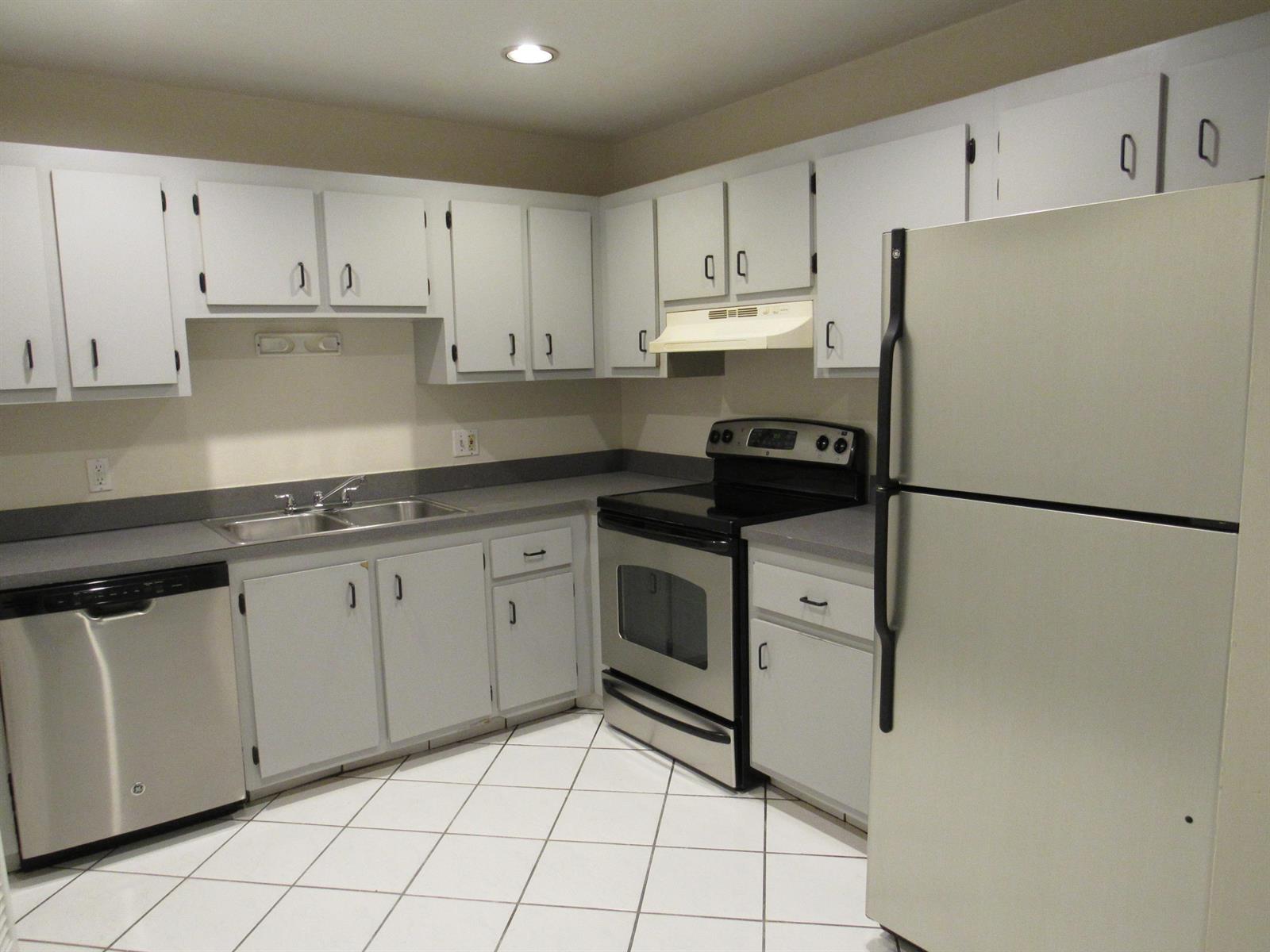 A kitchen features white cabinets, stainless steel appliances, grey countertops, and white tiled flooring — 1065 Manor Drive, Palm Springs FL 33461, PALM SPRINGS, FL