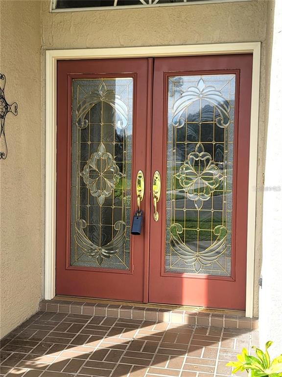 A pair of red double doors with decorative glass panels and gold hardware — 1501 DEERBOURNE DRIVE, WESLEY CHAPEL, FL