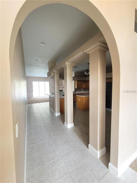 An arched entryway leads to a tiled hallway and an open kitchen with wooden cabinets — 1501 DEERBOURNE DRIVE, WESLEY CHAPEL, FL