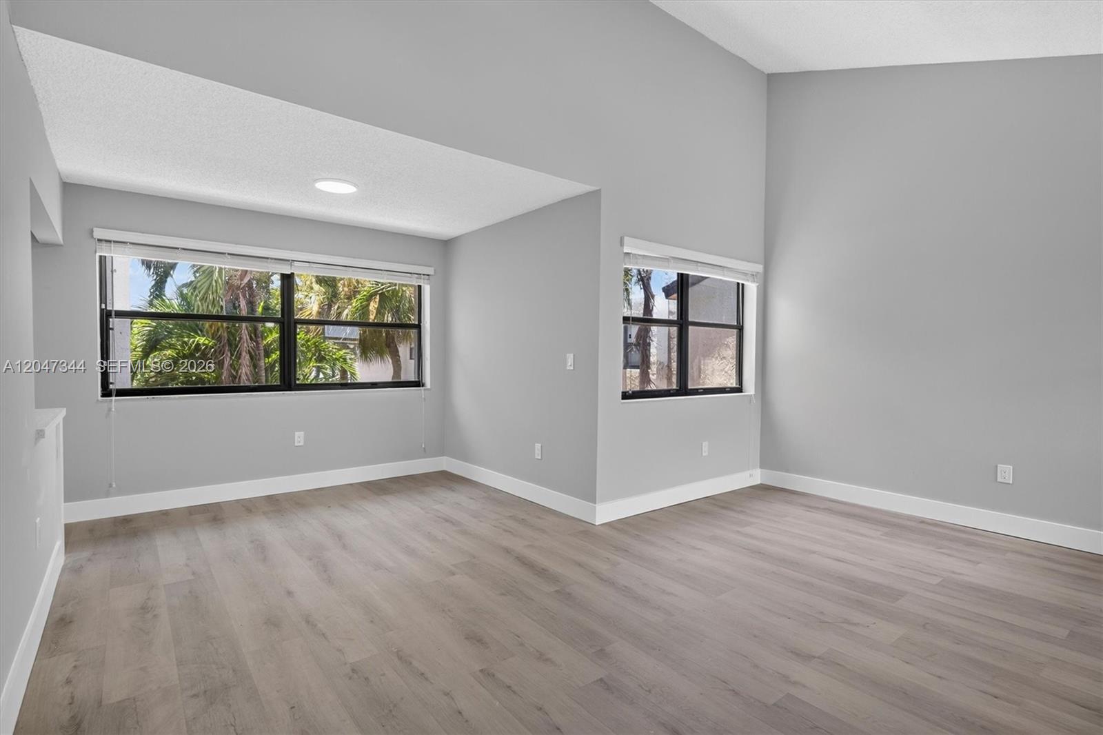 An empty room features light gray walls, wood-look flooring, and two windows with blinds — 10080 NW 9th St Cir # 204, Miami FL 33172, MIAMI, FL
