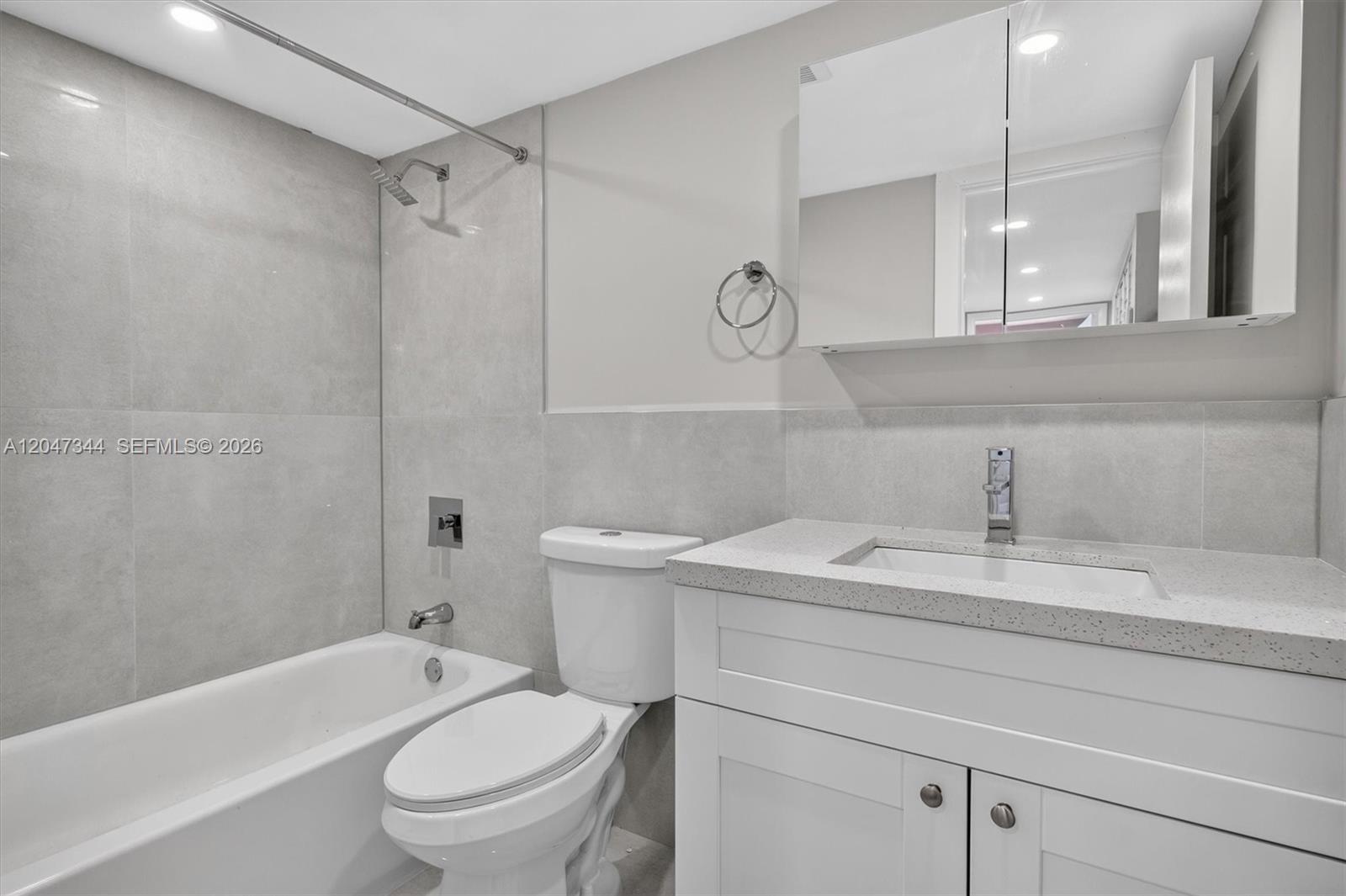 A modern bathroom features a white vanity, a toilet, and a tiled bathtub shower combination — 10080 NW 9th St Cir # 204, Miami FL 33172, MIAMI, FL