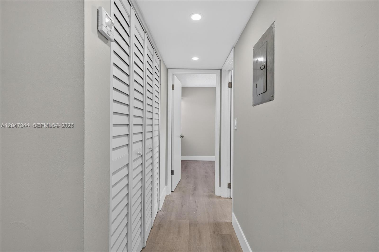 A hallway features light wood-look flooring, white louvered closet doors, and recessed ceiling lighting — 10080 NW 9th St Cir # 204, Miami FL 33172, MIAMI, FL
