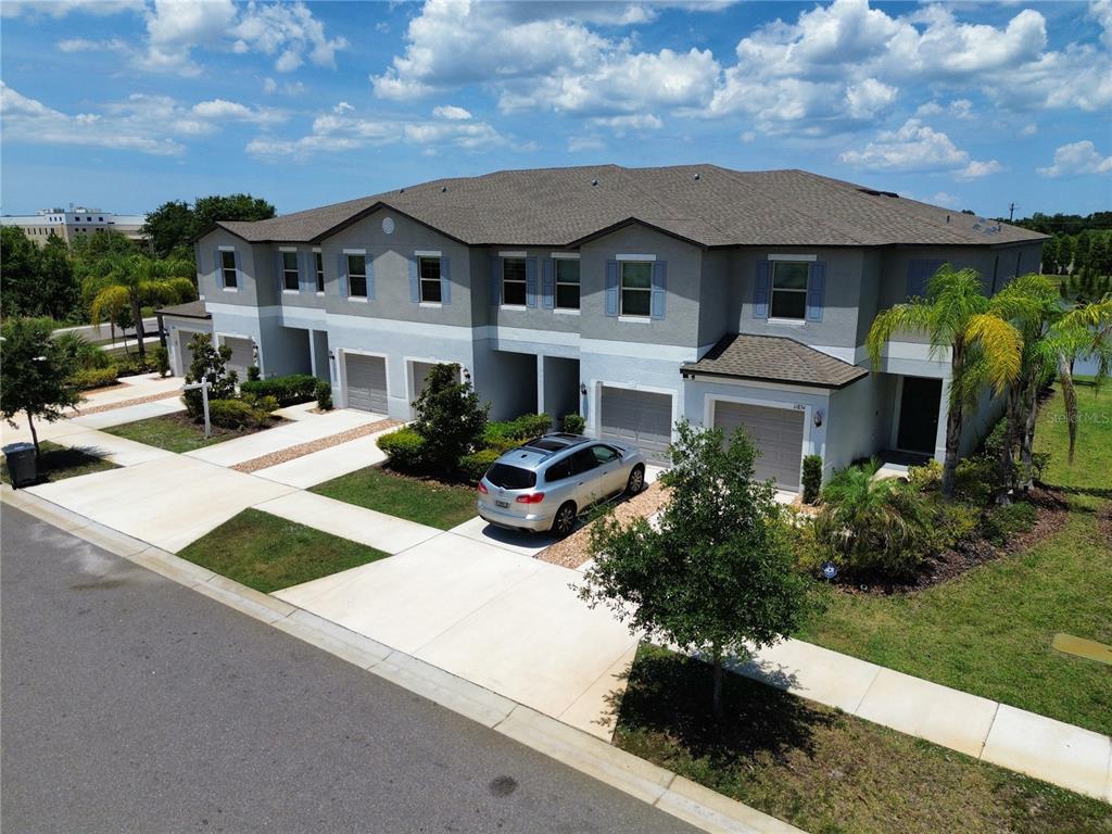 An aerial view of a multi-unit townhouse building with gray siding and attached garages — 11826 DUMAINE VALLEY ROAD, RIVERVIEW, FL