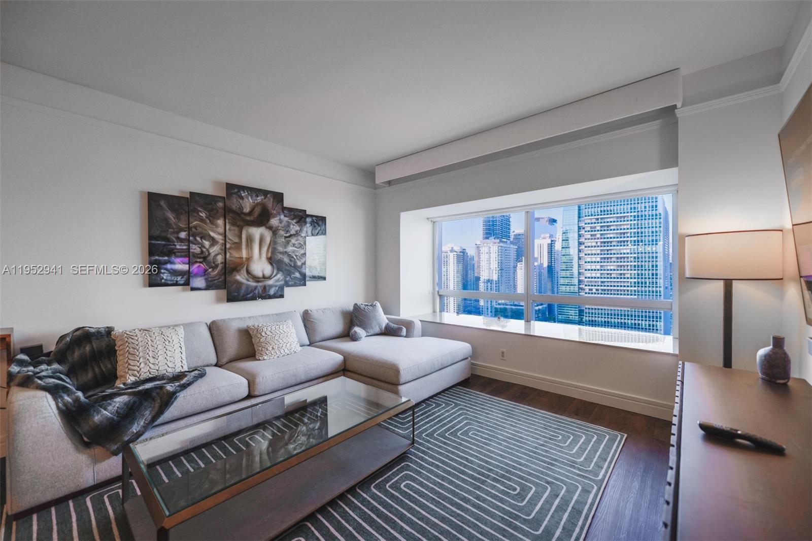 A living room features a grey sectional sofa, a glass coffee table, and city views — 1435 Brickell Ave # 3510, Miami FL 33131, MIAMI, FL