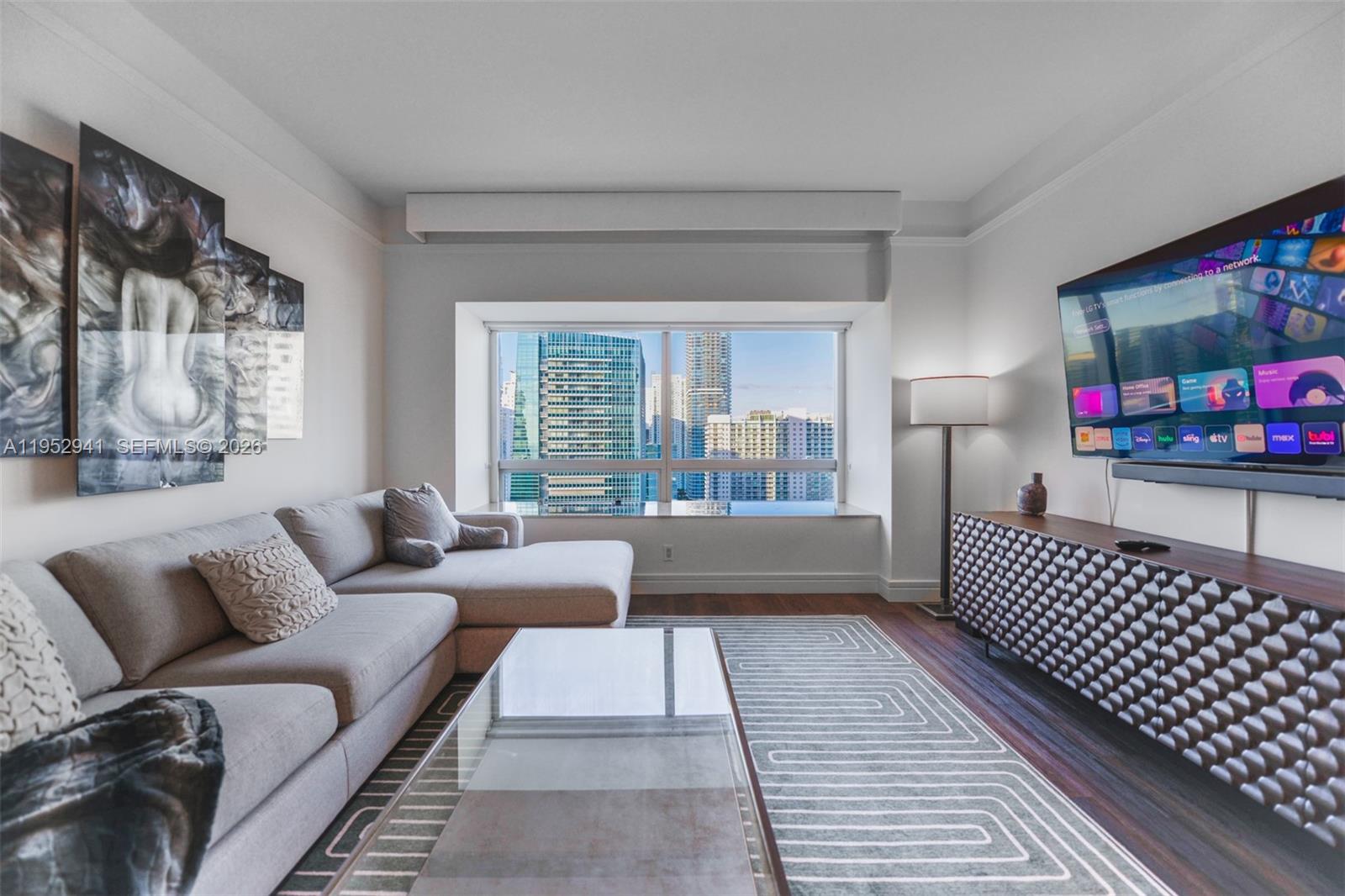 A living room features a sectional sofa, a glass coffee table, and a city view — 1435 Brickell Ave # 3510, Miami FL 33131, MIAMI, FL