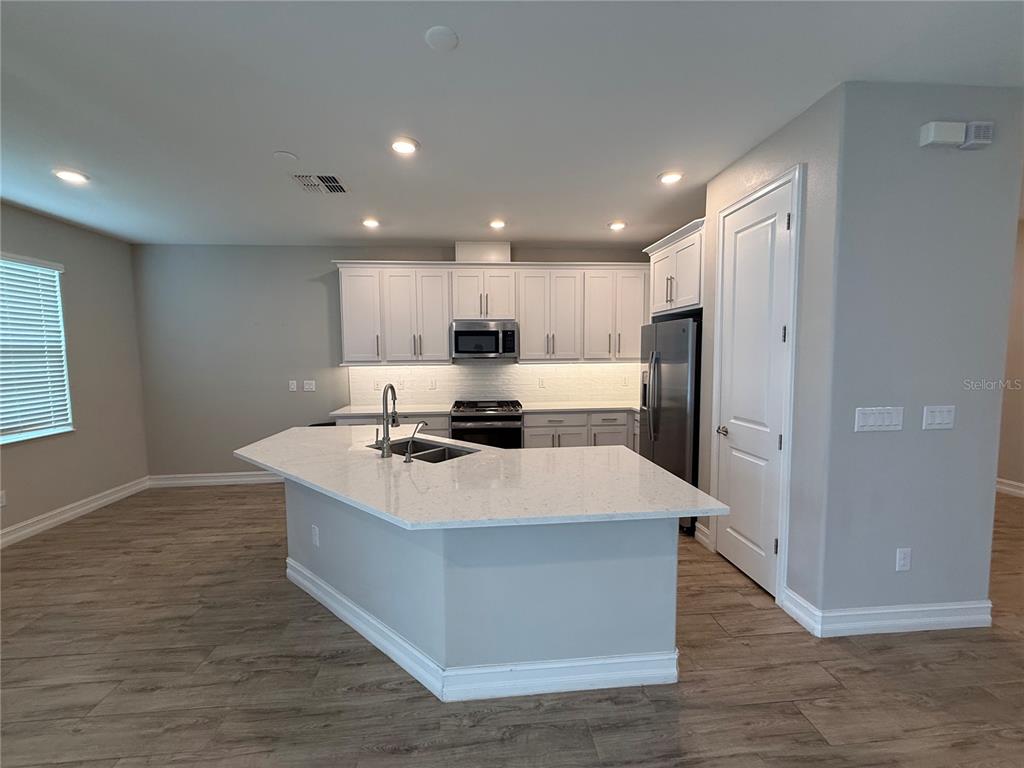 A two-story tan stucco house with dark trim, a hedge, and a storm drain — 4599 ALMADA LANE, WESLEY CHAPEL, FL