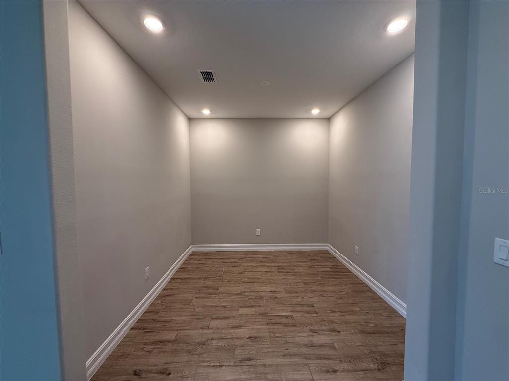 A covered concrete patio features recessed lighting and a sliding glass door — 4599 ALMADA LANE, WESLEY CHAPEL, FL