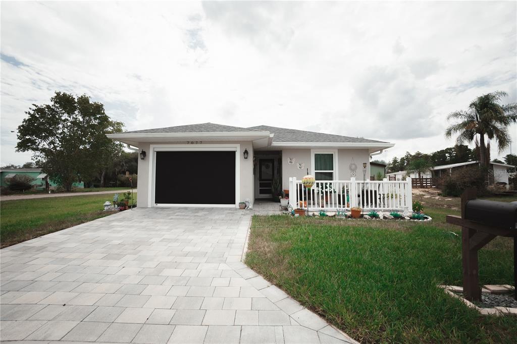 A single-story house with a paved driveway, a garage, and a white front porch railing — 7077 TAMARIND WAY, LAKE WALES, FL