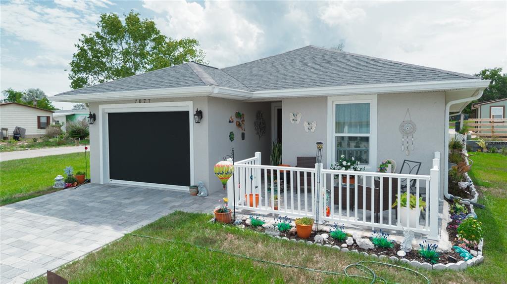 A single-story house features a paved driveway, a garage with a screen, and a front patio — 7077 TAMARIND WAY, LAKE WALES, FL