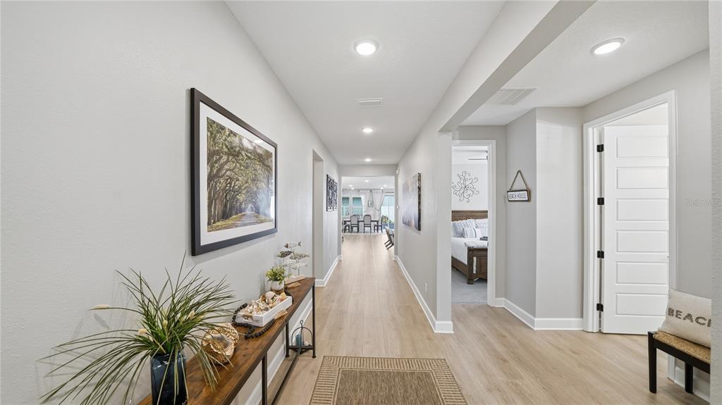 A bright hallway with light wood flooring leads toward a dining area and bedroom — 40 MOANA COURT S, PALM COAST, FL