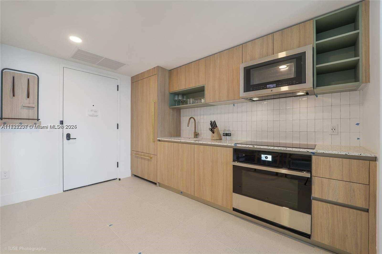 A modern kitchen features light wood cabinetry, stainless steel appliances, and a white tiled backsplash — 159 NE 6 # 3913, Miami FL 33132, MIAMI, FL