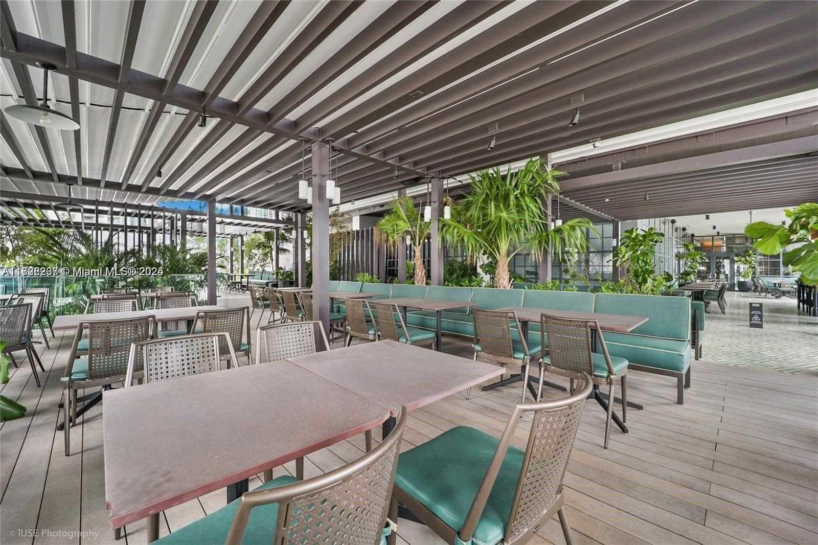 An outdoor patio features a slatted roof, dining tables, and chairs with green cushions — 159 NE 6 # 3913, Miami FL 33132, MIAMI, FL