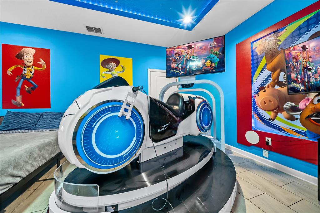 A bedroom features a Tron-themed motorcycle arcade game, blue walls, and Toy Story wall art — 4526 NARRATIVE LANE, KISSIMMEE, FL