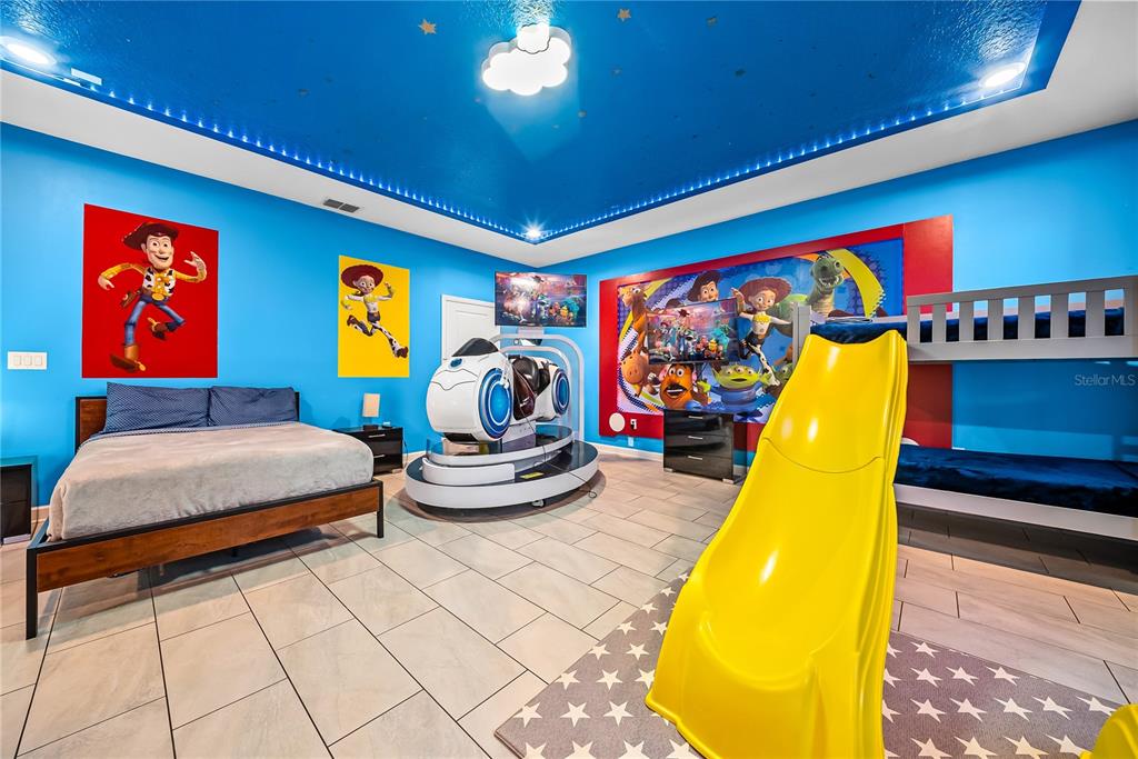 A Toy Story-themed bedroom features a bed, bunk bed, yellow slide, and gaming simulator — 4526 NARRATIVE LANE, KISSIMMEE, FL