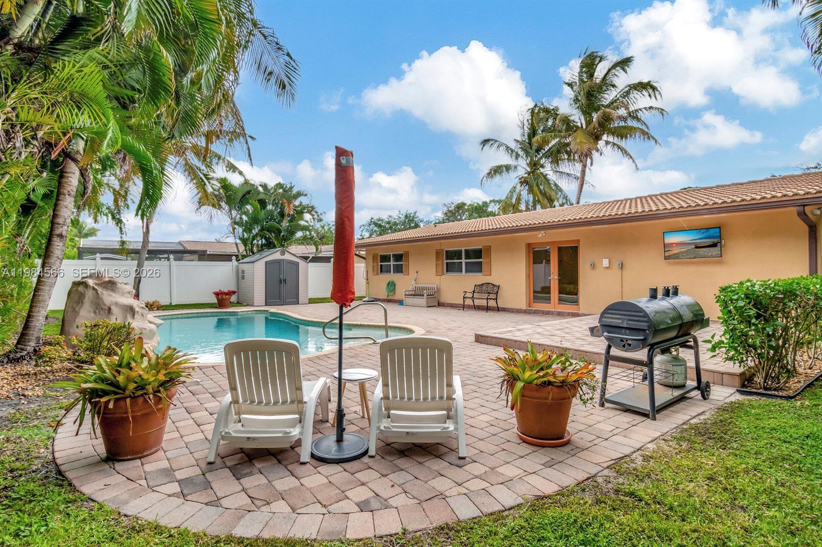 A backyard patio features a swimming pool, lounge chairs, a grill, and palm trees — 11 Forest Hills Ln, Boca Raton FL 33431, BOCA RATON, FL