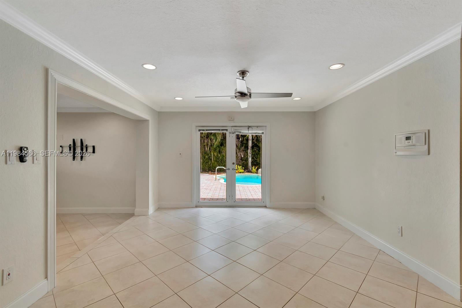A bright room with light tile floors, a ceiling fan, and glass doors overlooking a pool — 11 Forest Hills Ln, Boca Raton FL 33431, BOCA RATON, FL