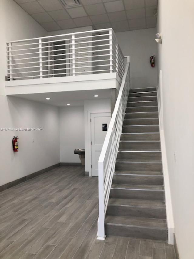 A room with gray wood-look tile flooring, a staircase, and an upper-level mezzanine with railings — 2201 NW 27th Ave # 2201, Miami FL 33142, MIAMI, FL