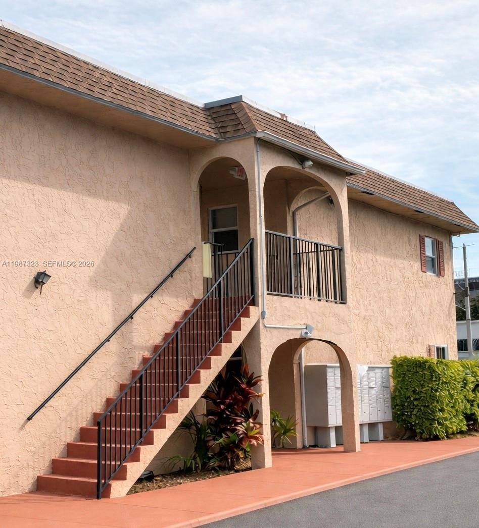 An exterior view of a two-story stucco building with an outdoor staircase and arched entryways — 550 SW 2nd Ave # 1210, Boca Raton FL 33432, BOCA RATON, FL