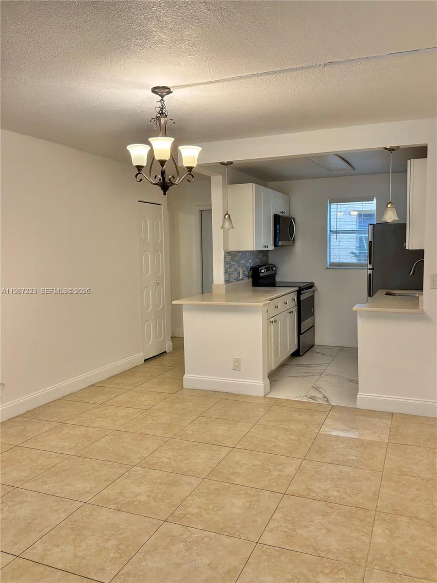 A kitchen with white cabinets and a dining area with a chandelier — 550 SW 2nd Ave # 1210, Boca Raton FL 33432, BOCA RATON, FL