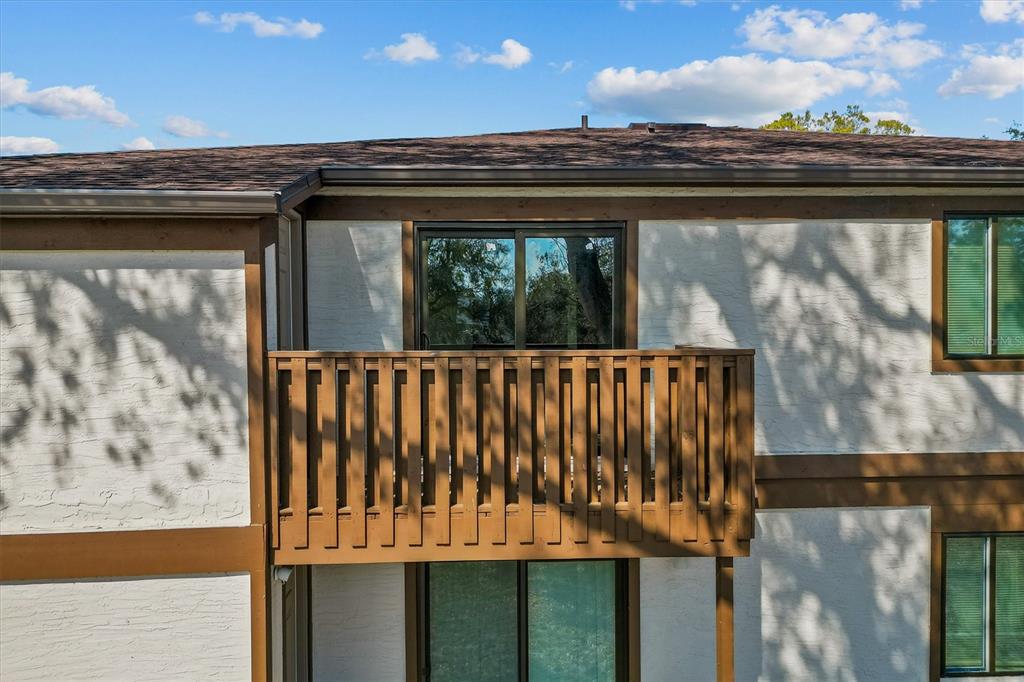 An exterior view of a two-story building featuring a wooden balcony and sliding glass doors — 4903 LAKE RIDGE ROAD UNIT GE, ORLANDO, FL