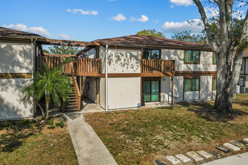 A two-story apartment building with a wooden balcony, outdoor staircase, and a palm tree — 4903 LAKE RIDGE ROAD UNIT GE, ORLANDO, FL