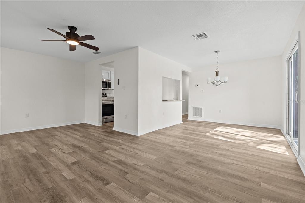 An empty living and dining area features light wood-look flooring, white walls, and a ceiling fan — 4903 LAKE RIDGE ROAD UNIT GE, ORLANDO, FL