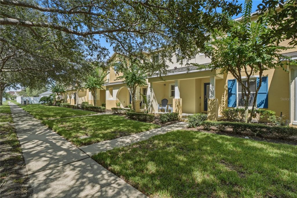 A row of two-story townhomes with yellow stucco exteriors, blue shutters, and covered front porches — 2517 ABEY BLANCO DRIVE, ORLANDO, FL