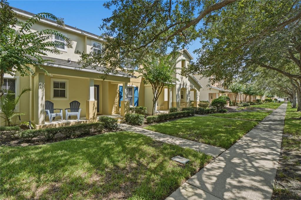 A row of yellow townhouses with front porches and blue shutters along a sidewalk — 2517 ABEY BLANCO DRIVE, ORLANDO, FL