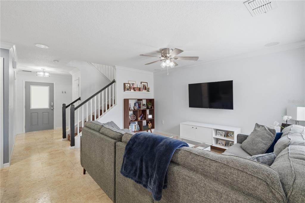 A living room features a gray sectional sofa, a wall-mounted television, and a staircase — 2517 ABEY BLANCO DRIVE, ORLANDO, FL
