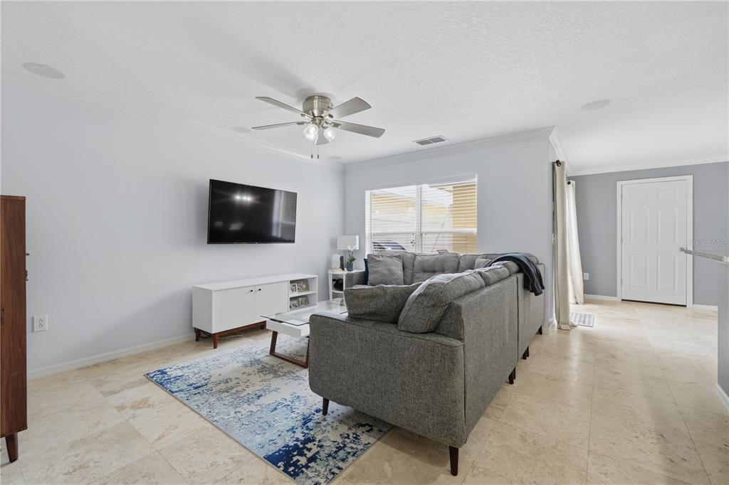 A living room features a gray sectional sofa, a wall-mounted television, and tile flooring — 2517 ABEY BLANCO DRIVE, ORLANDO, FL