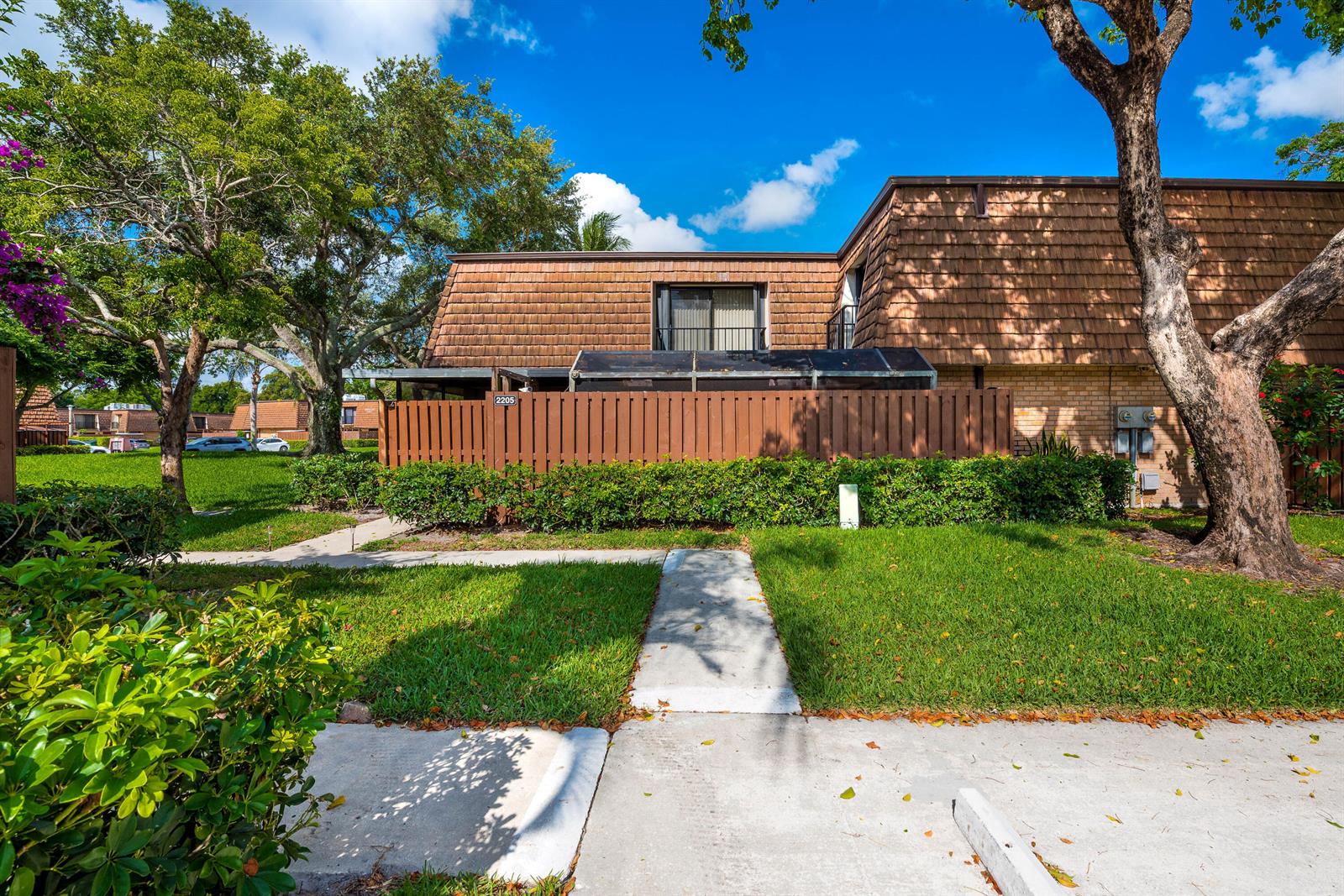 A two-story townhouse exterior features a brown shingled mansard roof and a private fenced patio — 2205 22nd Lane, FL 33463, FL